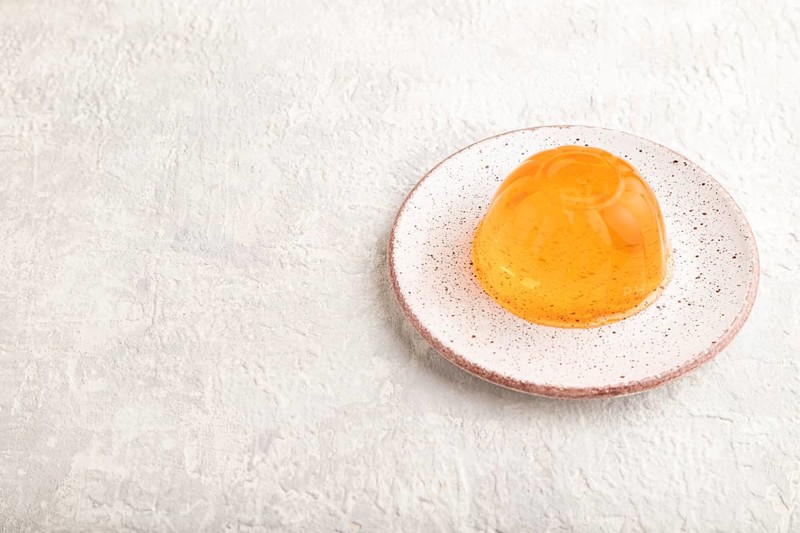 Papaya and orange jelly on gray concrete background. side view, copy space