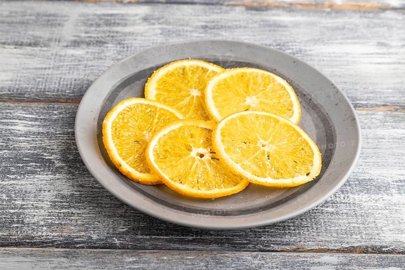 Orange chips on a gray plate on a gray wooden background. Side view, close up
