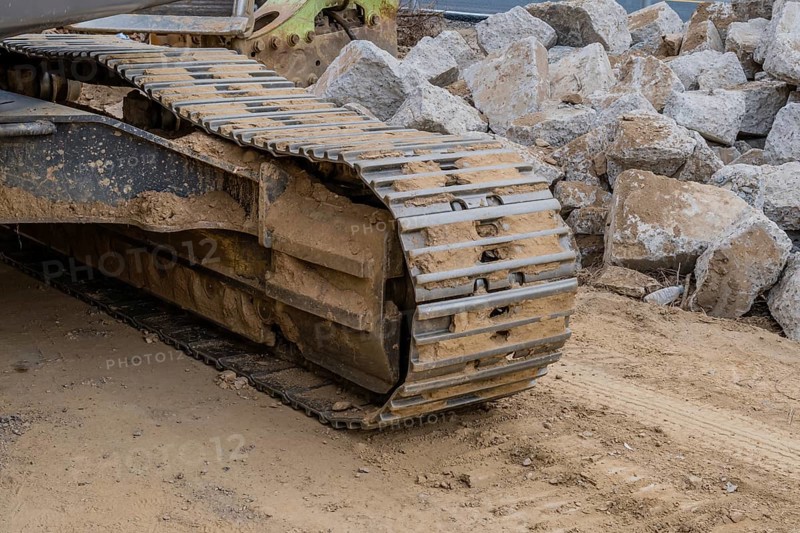 Track assembly of backhoe in front of large pieces if concrete at construction site