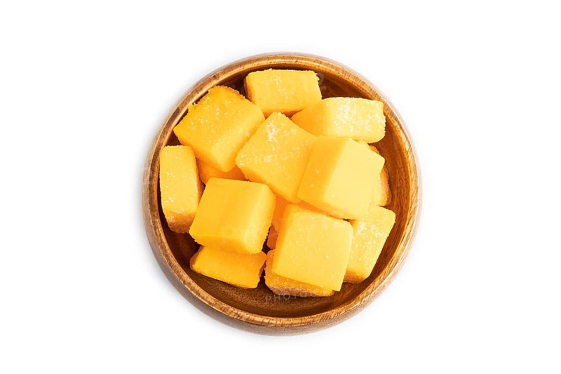 Dried and candied mango cubes in wooden bowls isolated on white background. Top view, flat lay, close up, vegan, vegetarian food concept