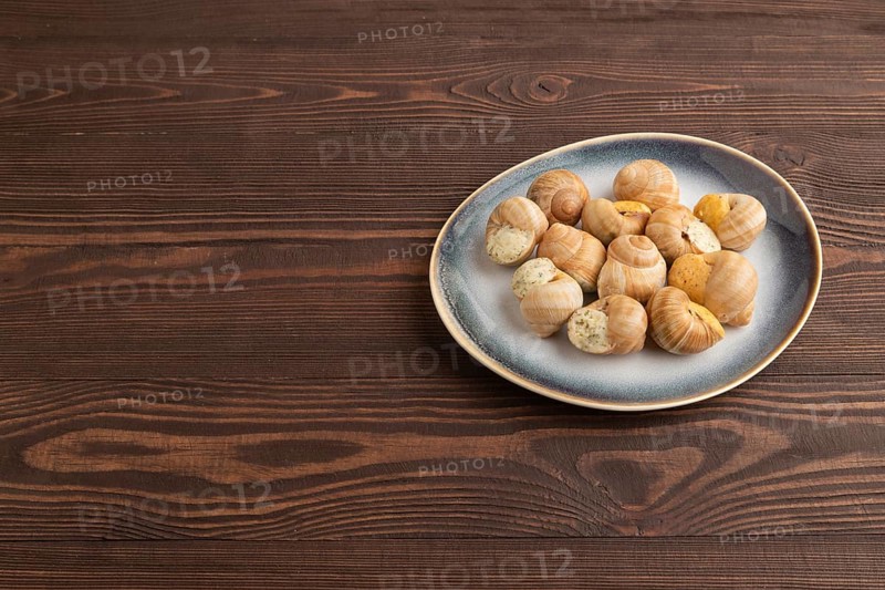 Grape (Burgundy) snails with butter and cheese on brown wooden background. Side view, copy space