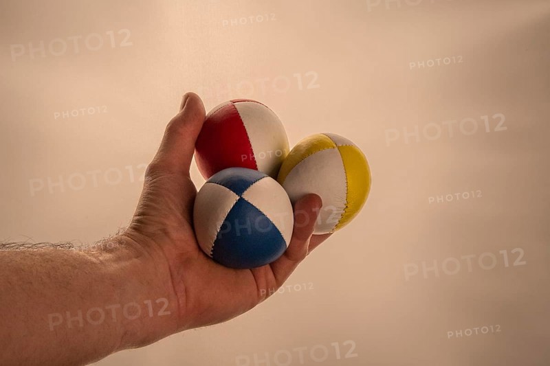 Male hand holding 3 colourful juggling balls, white background, studio shot, Germany, Europe