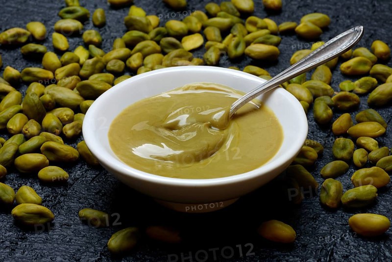 Pistachio cream in small bowls with spoon, pistachios