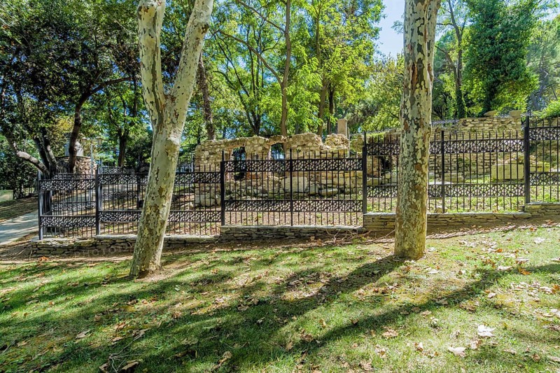 Ruins of ancient roman era behind black iron fence in public park in Istanbul, Tuerkiye