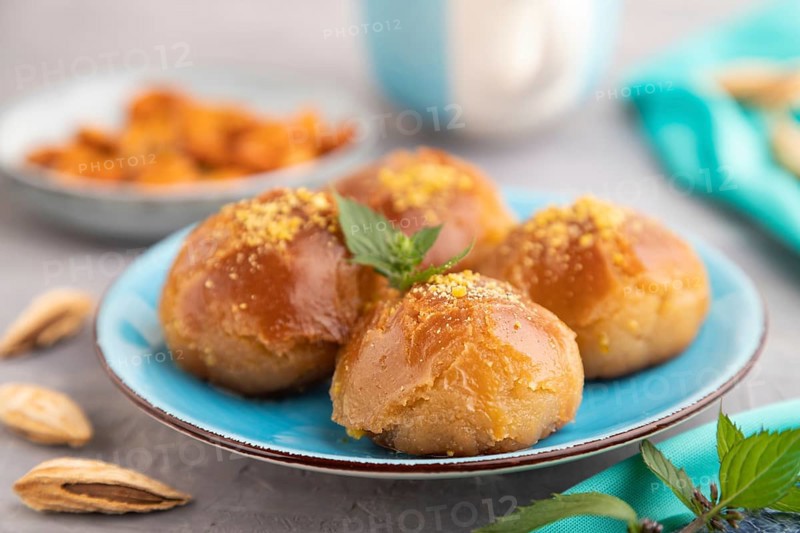Homemade traditional turkish dessert sekerpare with almonds and honey, cup of green tea on gray concrete background and blue textile. side view, selective focus