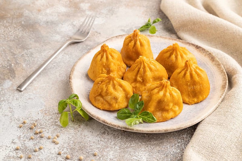Fried manti dumplings with pepper, basil on gray concrete background and linen textile. Side view, close up