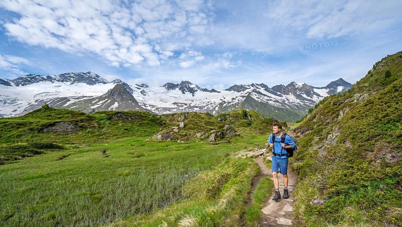 Mountaineer on hiking trail in picturesque mountain landscape, mountain peaks with snow and glacier Hornkees and Waxeggkees, summit Grosser Moeseler and Hornspitzen, Berliner Hoehenweg, Zillertal Alps, Tyrol, Austria, Europe