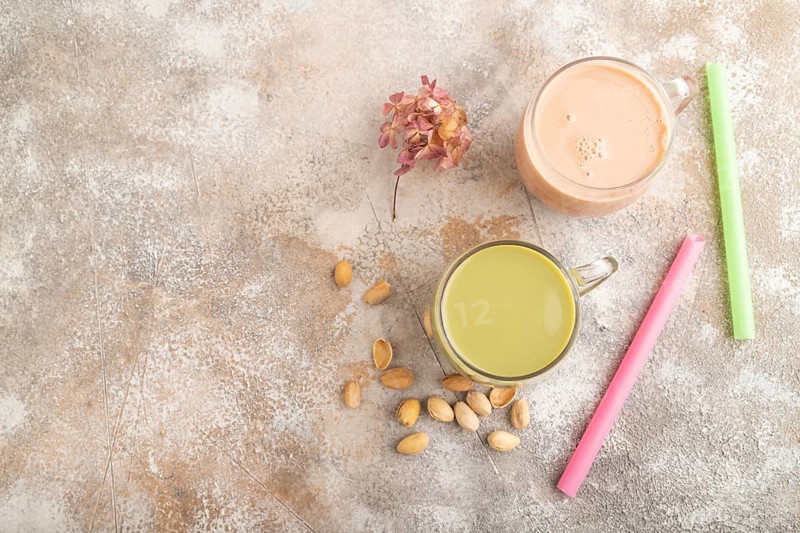 Bubble tea with pistachio and caramel in glass on brown concrete background. Healthy drink concept. Top view, flat lay, copy space