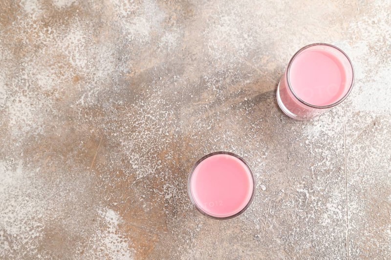 Sweet strawberry liqueur in glass on a gray concrete background. top view, copy space, flat lay
