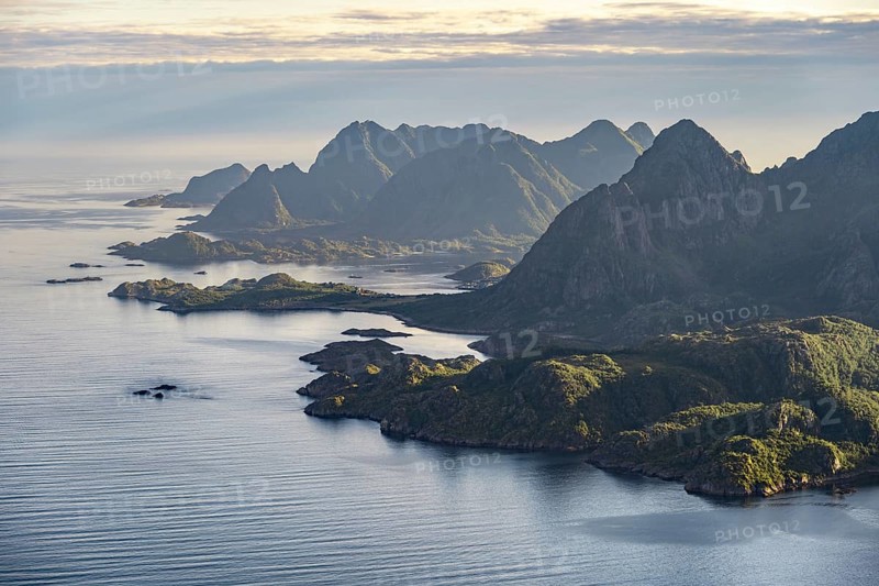 View of the coast in Ulvagsundet fjord and mountains in the evening light, Hurtigruten cruise ship in the fjord, view from the summit of Dronningsvarden or Stortinden, Vesteralen, Norway, Europe
