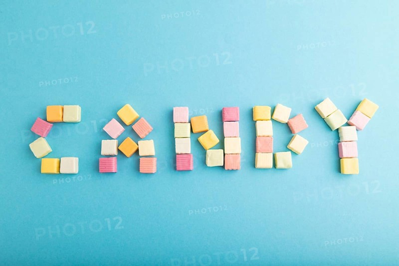 The inscription candy laid out with various fruit jelly chewing candies on blue pastel background. apple, banana, tangerine, top view, flat lay, copy space