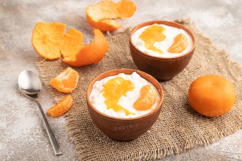 Grained cottage cheese with tangerine jam on brown concrete background and linen textile. side view, close up