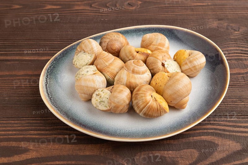 Grape (Burgundy) snails with butter and cheese on brown wooden background. Side view