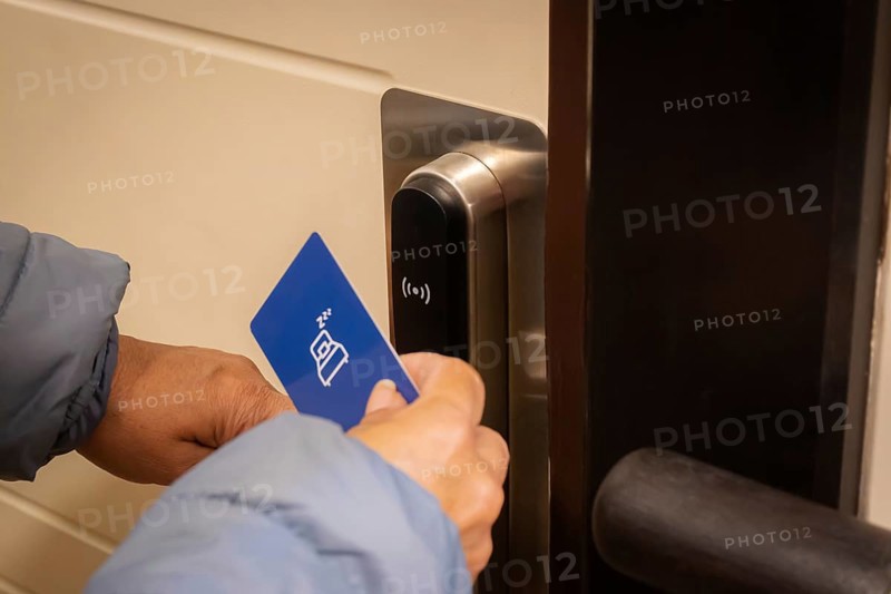 Cropped shot view of tourist woman using keycard to unlock an electronic door in luxury hotel