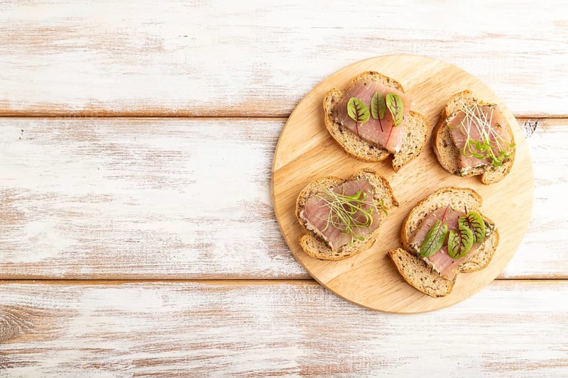 Bread sandwiches with jerky salted meat, sorrel and cilantro microgreen on white wooden background. top view, flat lay, copy space