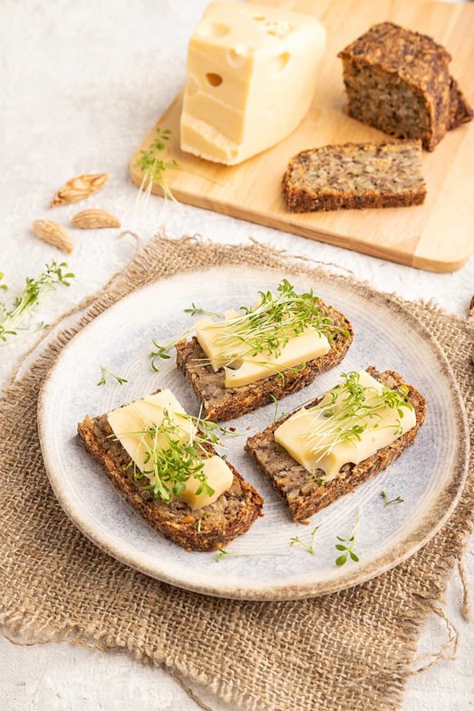 Grain bread sandwiches with cheese and watercress microgreen on gray concrete background and linen textile. side view, close up