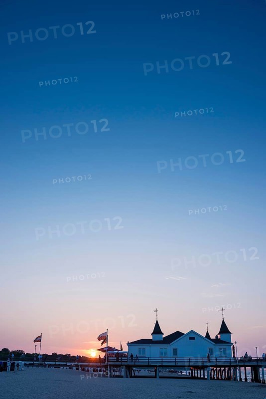 People strolling on a pier with buildings in the sunset, clear, blue, cloudless sky, pier Ahlbeck in the last sunlight, view from the eastern beach to the west, seaside resort Ahlbeck, island Usedom, Mecklenburg-Western Pomerania, Germany, Europe