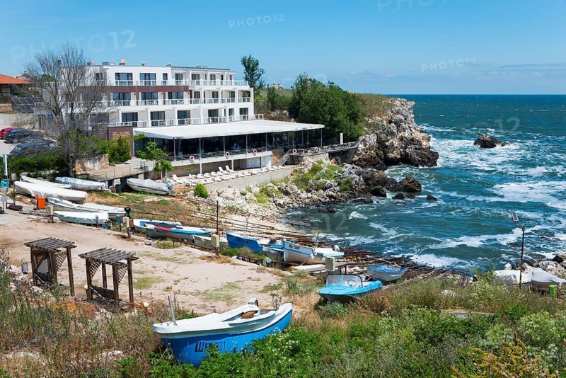 A hotel on the rocky coast with a view of the sea and several boats moored on the beach, harbour and hotel, Tyulenovo, Shabla, Dobrich, Black Sea, Bulgaria, Europe