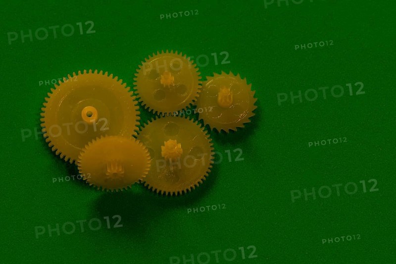 Yellow hard plastic cog sprocket wheels on green background