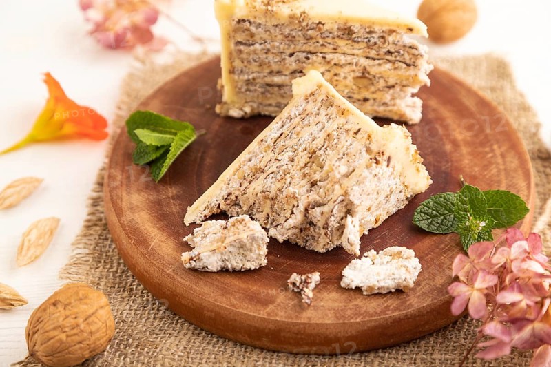Walnut and almond cake on white wooden background and linen textile. side view, close up, selective focus