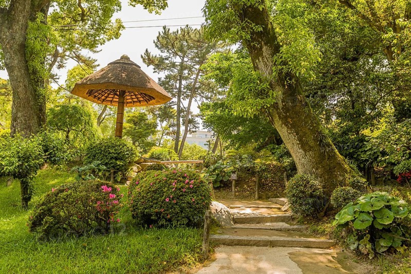 Thatch and bamboo umbrella covered rest area in Japanese garden in Hiroshima, Japan, Asia