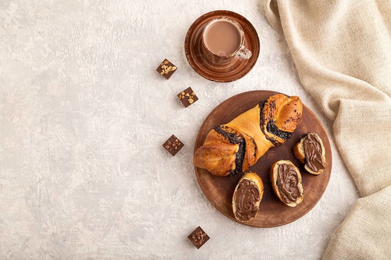 Homemade sweet bun with chocolate cream and cup of coffee on a gray concrete background and linen textile. top view, flat lay, copy space