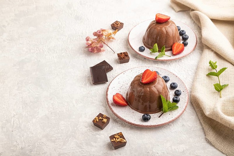 Chocolate jelly with strawberry and blueberry on gray concrete background and linen textile. side view, copy space