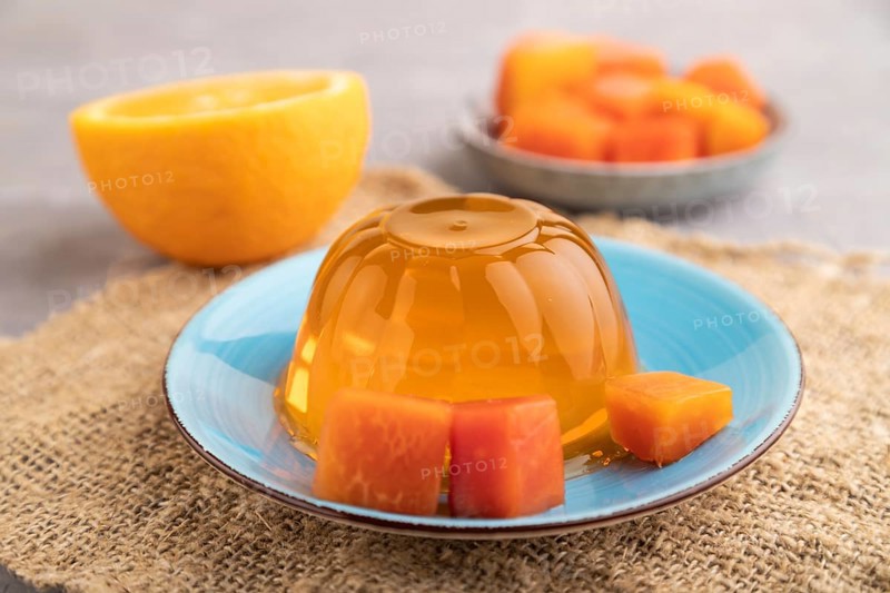 Papaya and orange jelly on gray concrete background and linen textile. side view, close up, selective focus