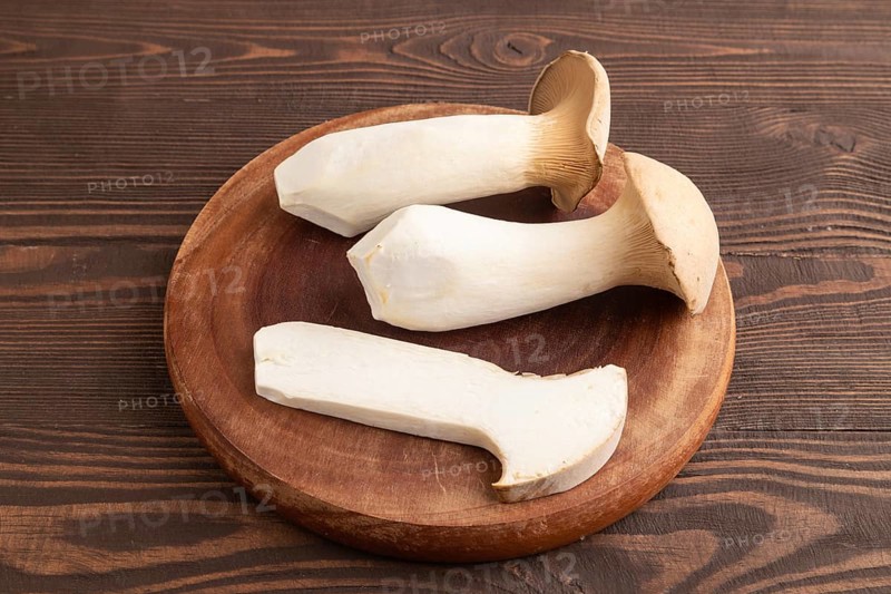 King Oyster mushrooms or Eringi (Pleurotus eryngii) on brown wooden background. Side view