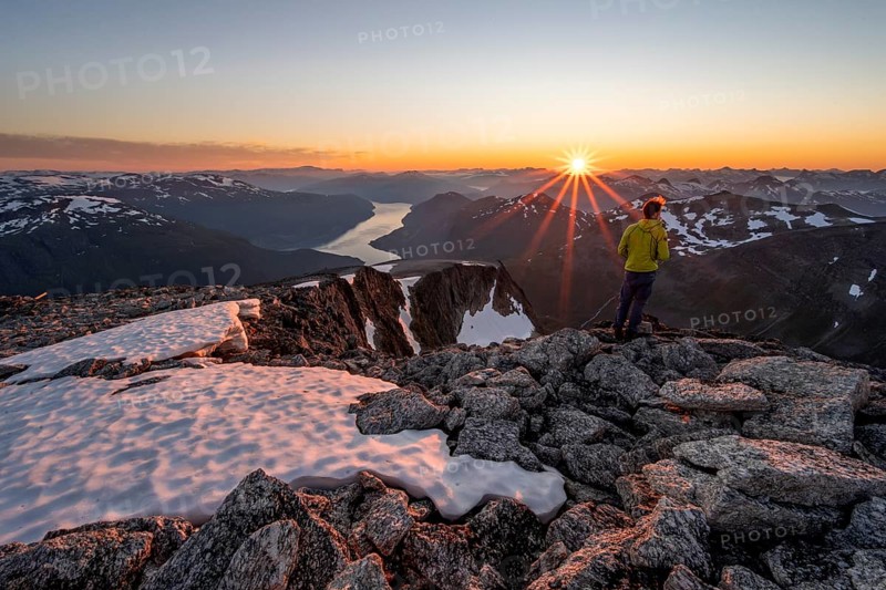 View of mountains and fjord Faleidfjorden, sun star at sunset, mountaineer at the summit of Skala, Loen, Norway, Europe