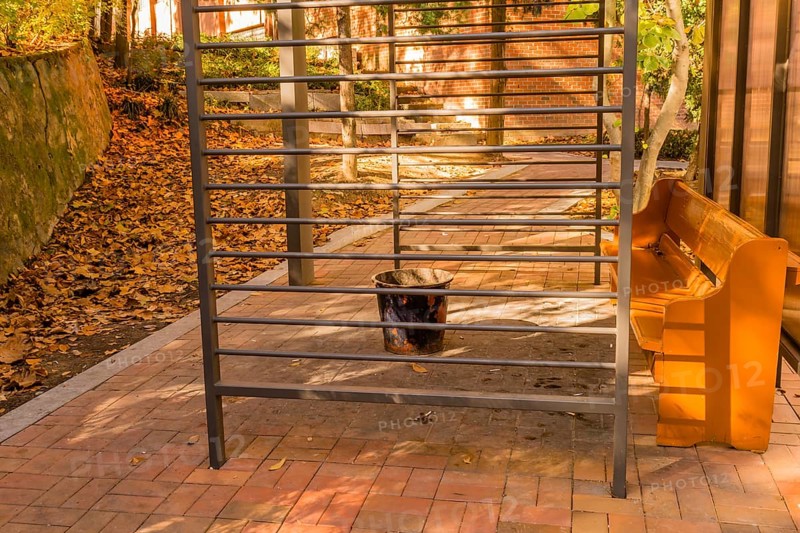 Dirty, littered public smoking area with wooden bench and ash can