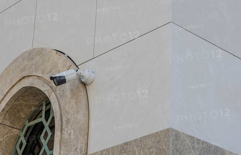 Closed circuit TV camera beside window frame of marble walled building in Istanbul, Tuerkiye