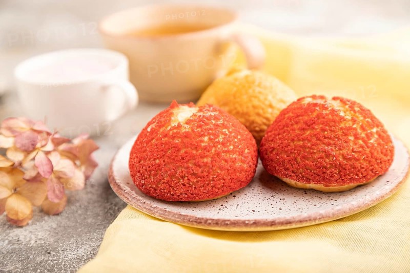 Traditional french custard dessert shu cake and cup of green tea on brown concrete background and yellow linen textile. side view, selective focus. Breakfast, morning, concept