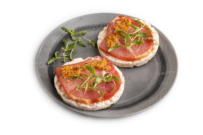 Puffed rice cake sandwiches with jerky salted meat, microgreen and mustard isolated on white background. side view, close up
