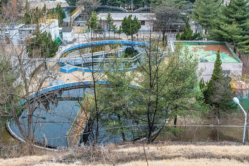 Water treatment plant with pools of water nestled among trees in rural setting. Shot from hill overlooking plant site