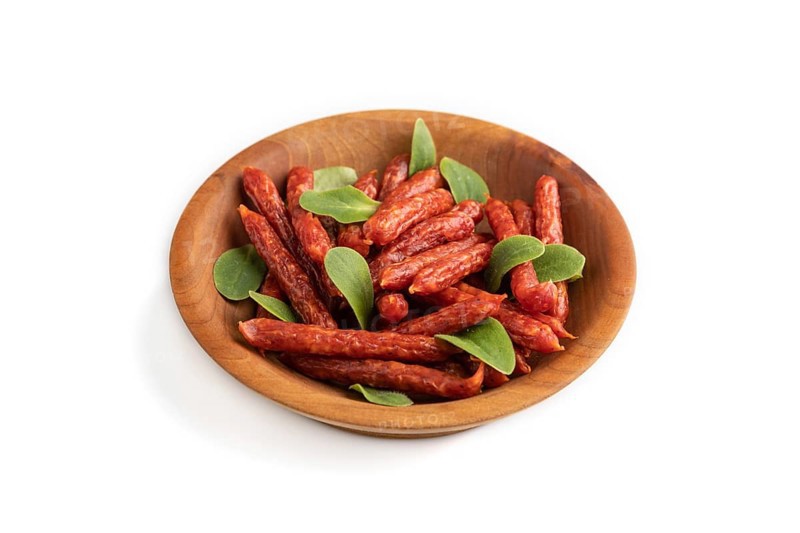 Small smoked sausage with borage microgreen isolated on white background. Side view, close up