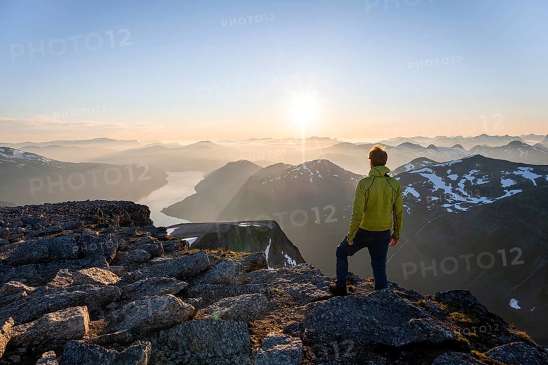 View of mountains and fjord Faleidfjorden, sun star at sunset, mountaineer at the summit of Skala, Loen, Norway, Europe
