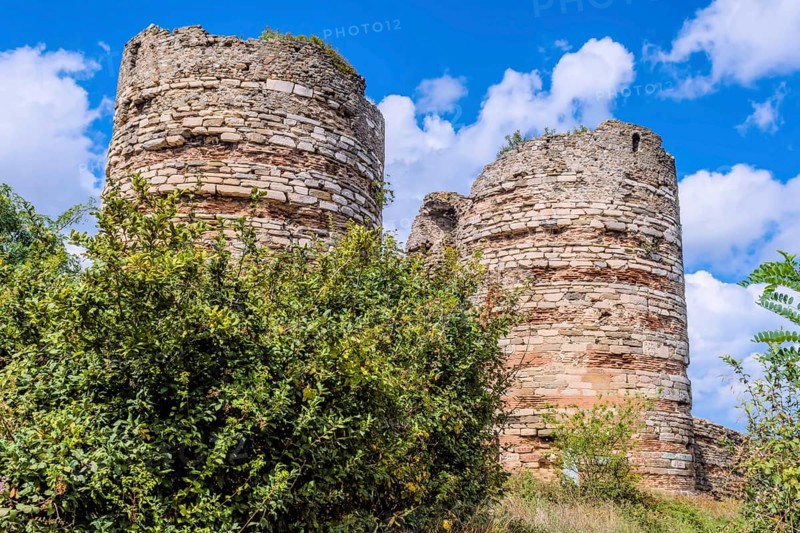 Remains of brick and stone castle towers on hillside under cloudy sky in Istanbul, Tuerkiye