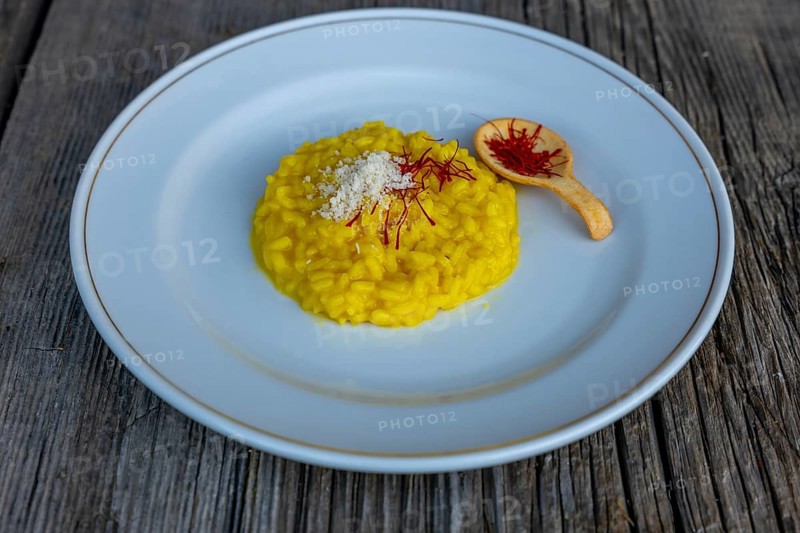 Elegant Plate with Risotto alla Milanese with Saffron and Parmesan Cheese on an Old Wood Table in Lugano, Ticino, Switzerland, Europe