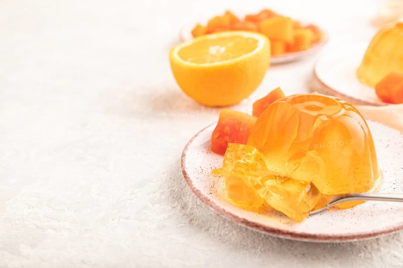Papaya and orange jelly on gray concrete background and orange linen textile. side view, flat lay, close up, selective focus