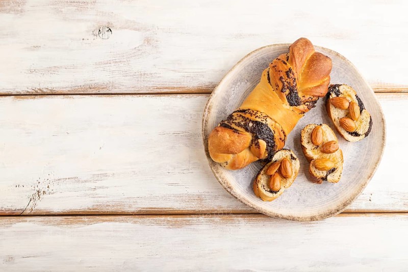 Homemade sweet bun with honey almonds on a white wooden background. top view, flat lay, copy space