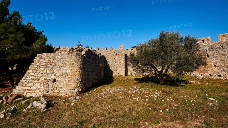 Part of the fortress wall surrounded by trees and grass, Chlemoutsi, High Medieval Crusader castle, Kyllini peninsula, Peloponnese, Greece, Europe