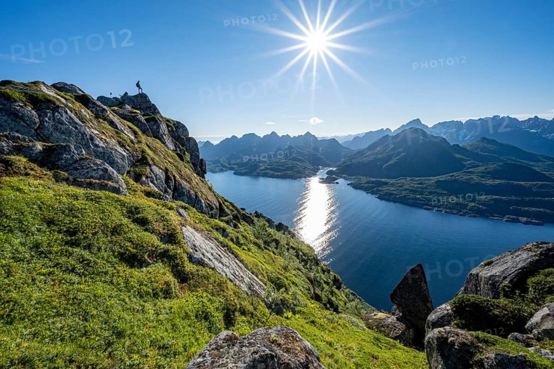 Mountaineer on the summit of Dronningsvarden or Stortinden, behind sea and fjord Umvagsundet, Sonnenstern, Vesteralen, Norway, Europe