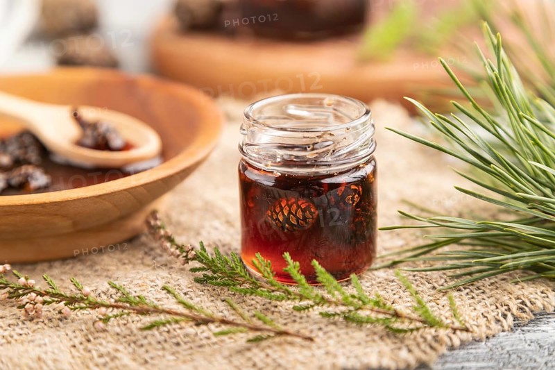 Pine cone jam with herbal tea on gray wooden background and linen textile. Side view, close up, selective focus