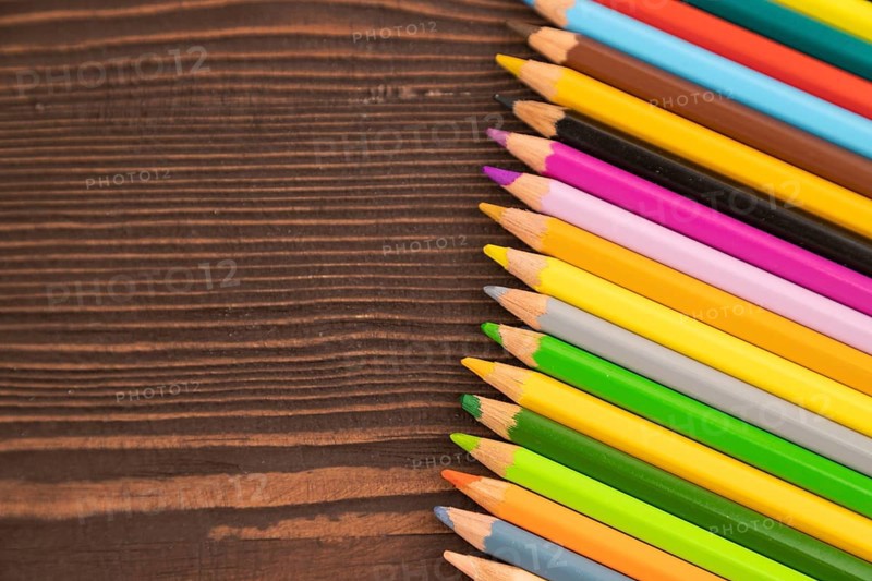 Set of watercolor pencils on brown wooden background. Top view, flat lay, copy space