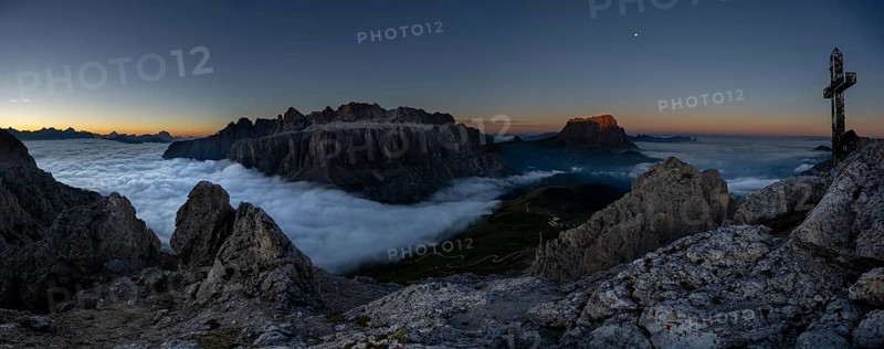 Summit cross of the large Cirrspitze with sunrise over a sea of fog and Dolomite peaks in the background, Corvara, Dolomites, Italy, Europe