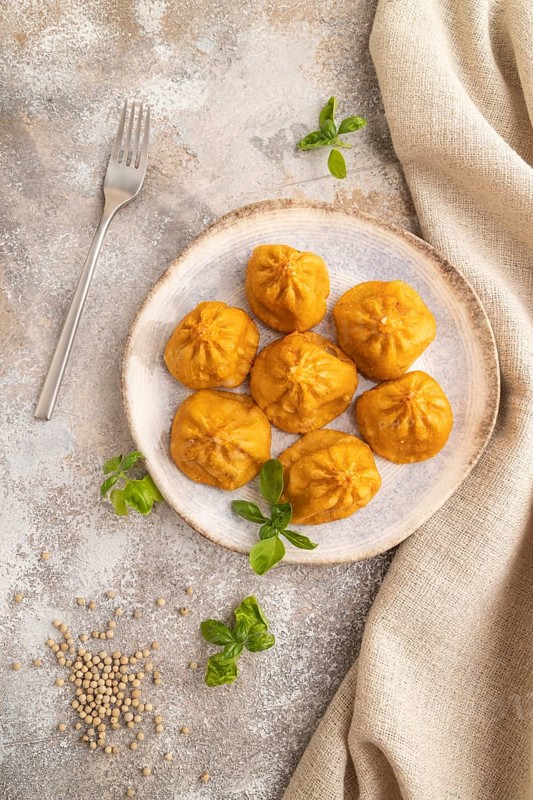 Fried manti dumplings with pepper, basil on gray concrete background and linen textile. Top view, flat lay, close up