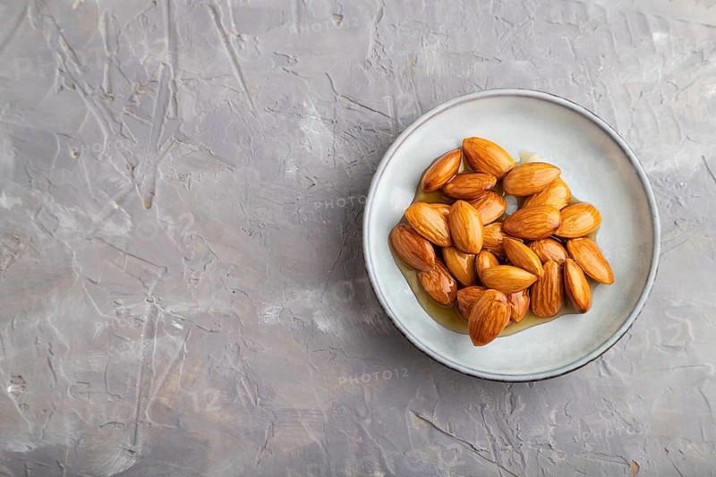 Almonds with honey on gray concrete background. top view, flat lay, close up, copy space