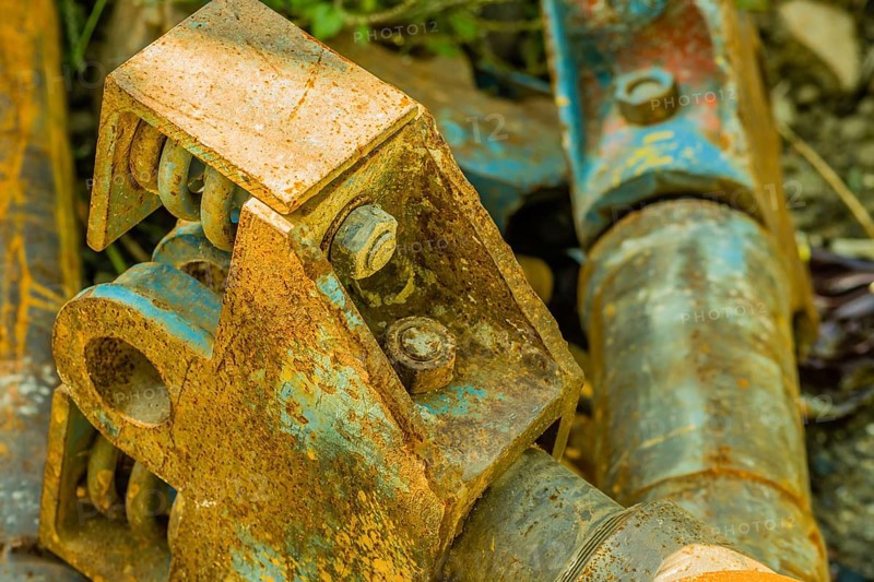 Closeup of rusted metal industrial machine parts discarded and laying on the ground