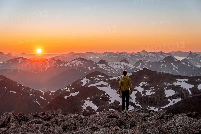 Mountaineer enjoying the view, mountain panorama at the summit of Skala at sunset, sun setting behind the mountains, Loen, Norway, Europe